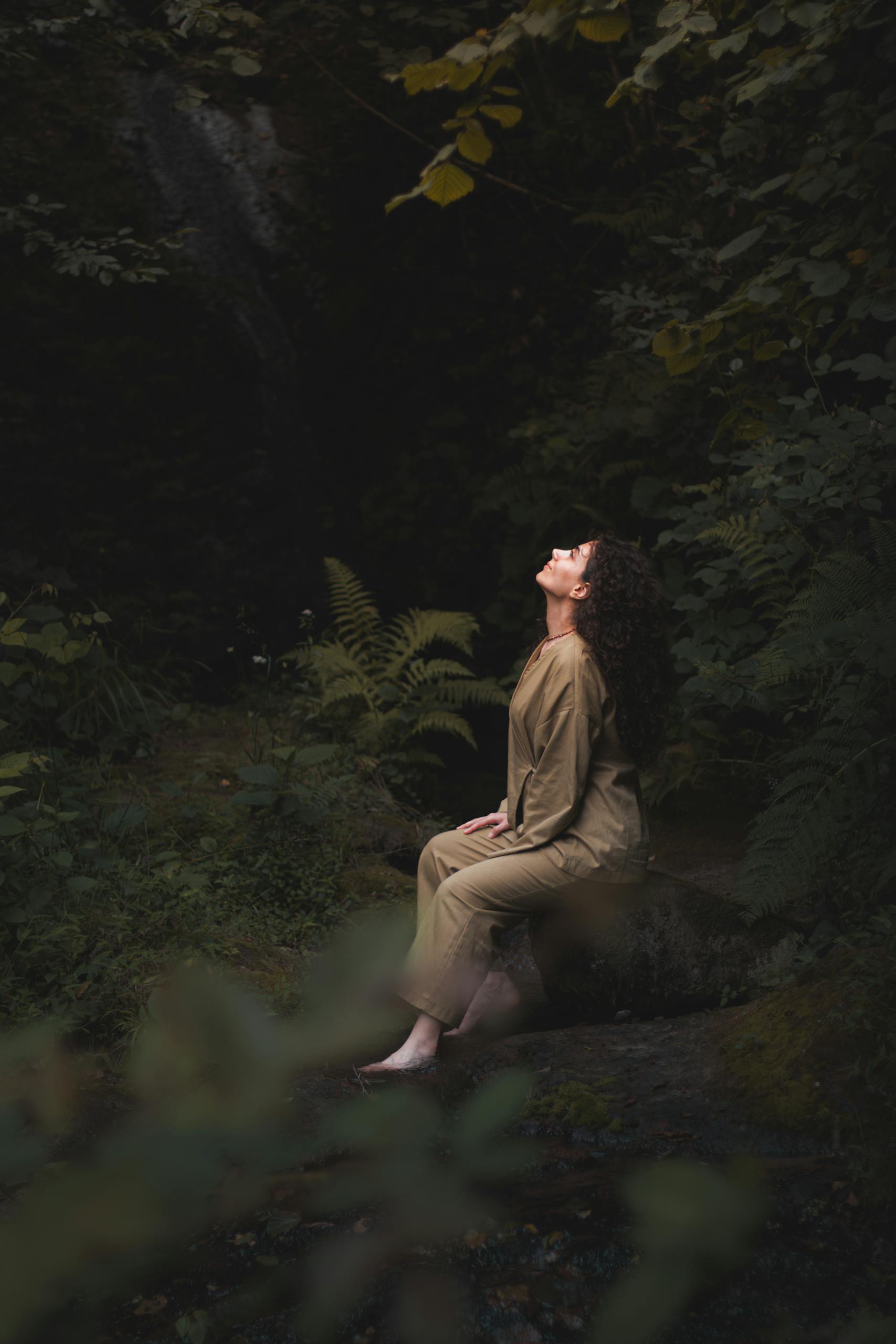 Young woman meditating in a tranquil forest setting, embracing nature's serenity.