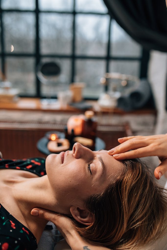 A serene moment of a spa face massage session indoors with soft candlelight.